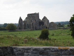 A beautiful abbey in the middle of a field with a stone fence. :)
